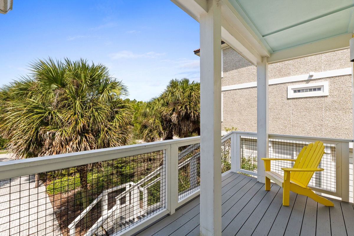 Your private balcony features a cheerful yellow chair where you can unwind while enjoying tropical palm views and gentle coastal breezes.