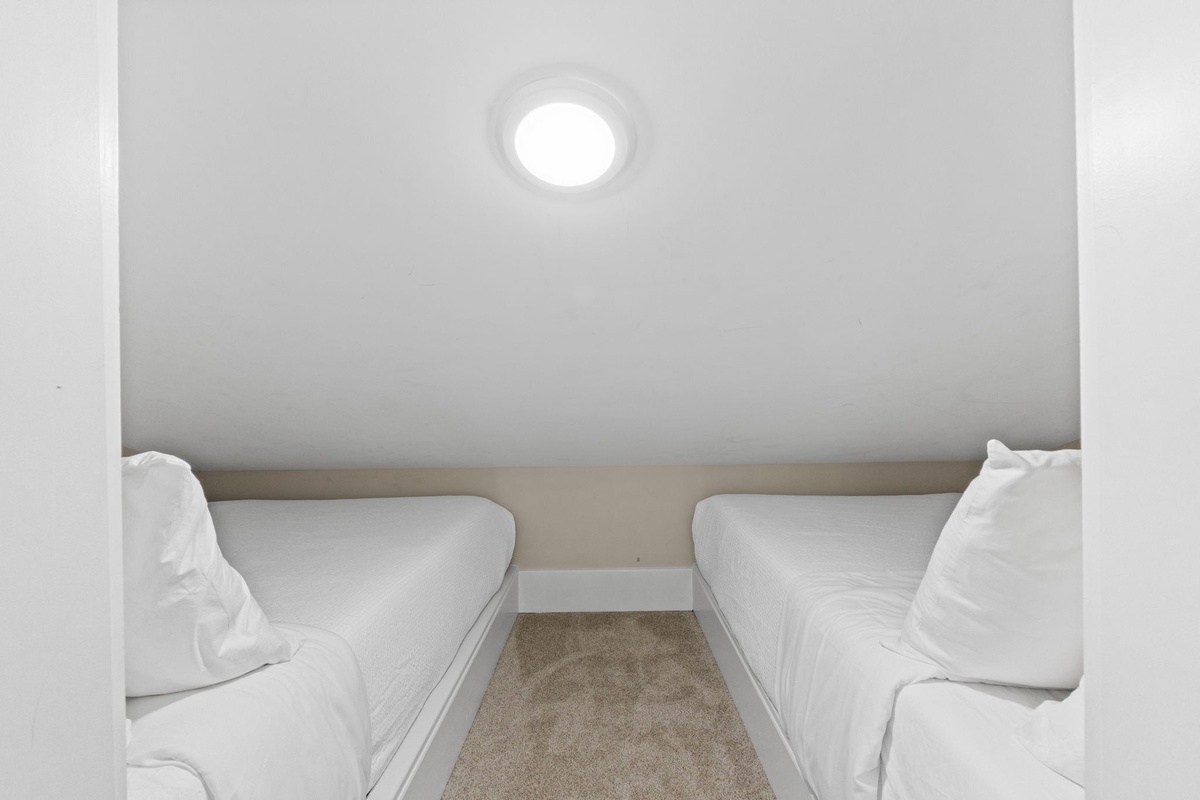 Cozy twin beds in a compact alcove create your perfect hideaway retreat with crisp white linens.