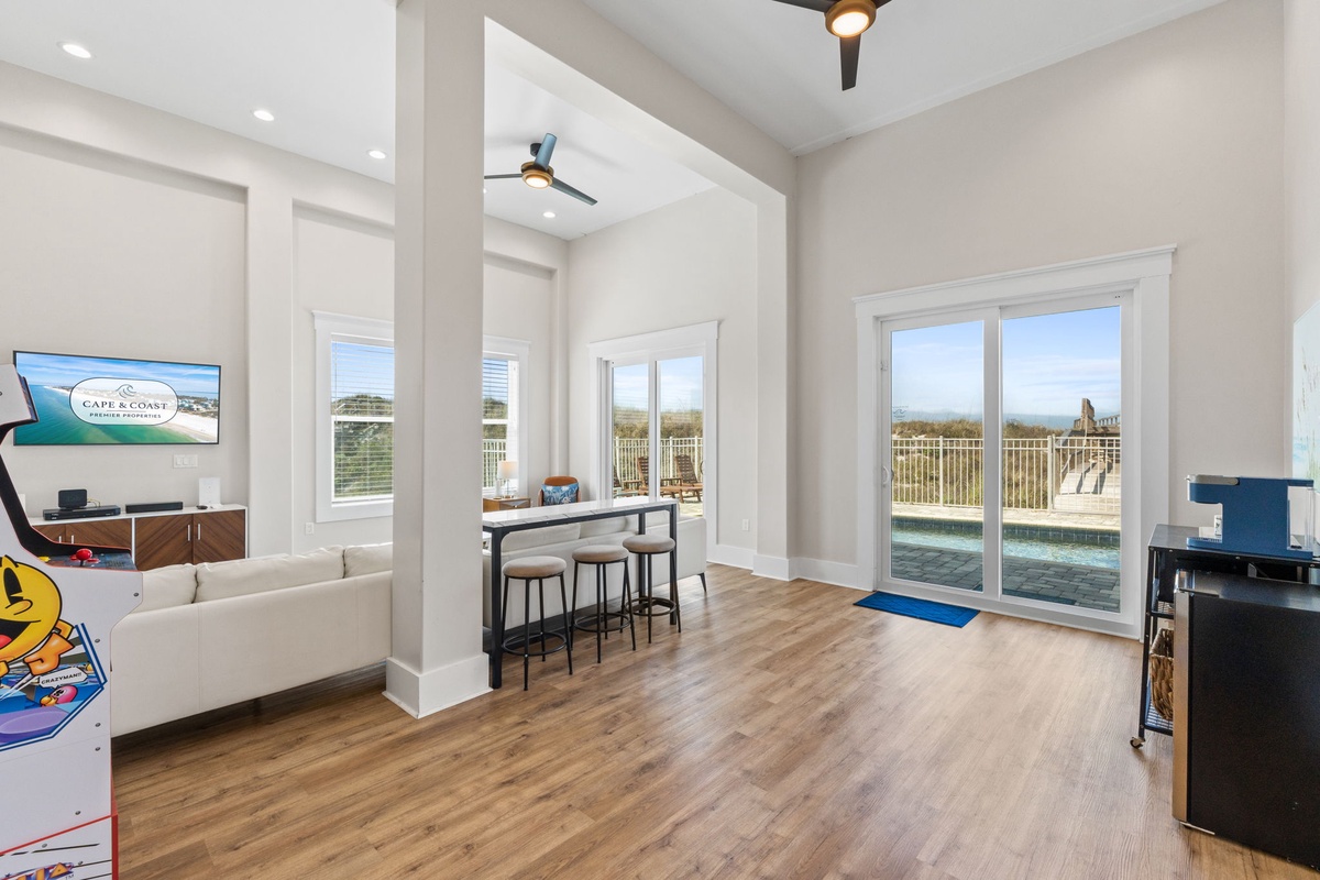 Your stylish game room beckons with arcade fun and stunning pool views through floor-to-ceiling windows.