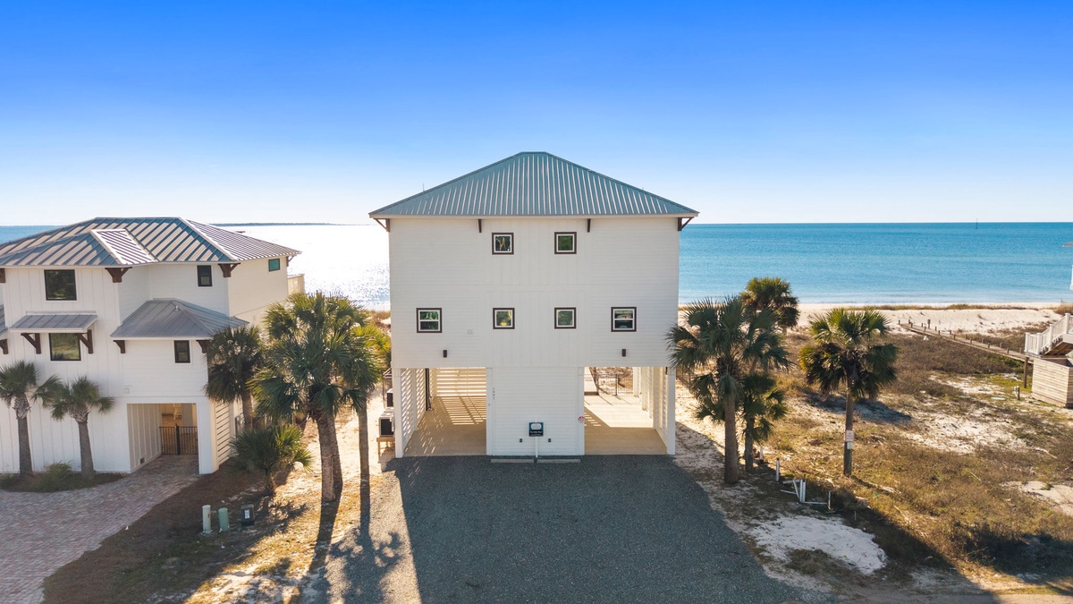 Beachfront property with tropical palms and stunning Gulf Coast views, featuring elevated design and private parking just steps from pristine white sand.