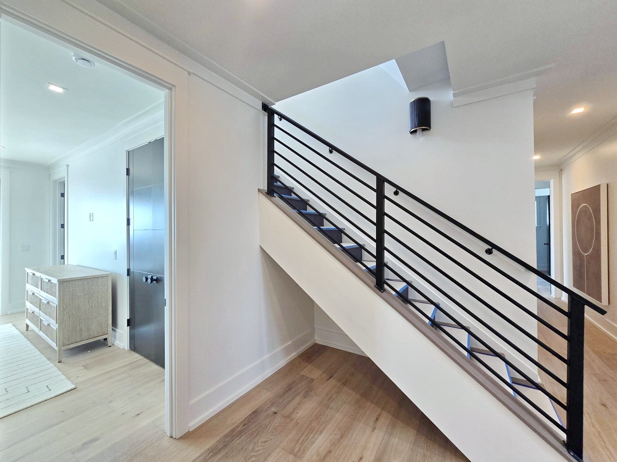 Your upstairs retreat awaits via sleek modern stairs with contemporary black railings and warm wood floors throughout.