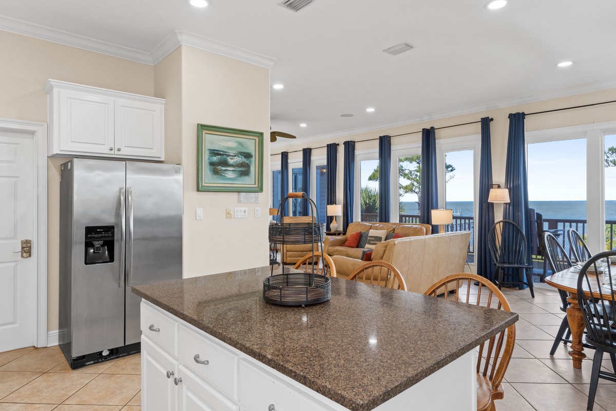 Your open kitchen flows seamlessly into the living area, where ocean views through floor-to-ceiling windows create a perfect backdrop for cooking and entertaining.