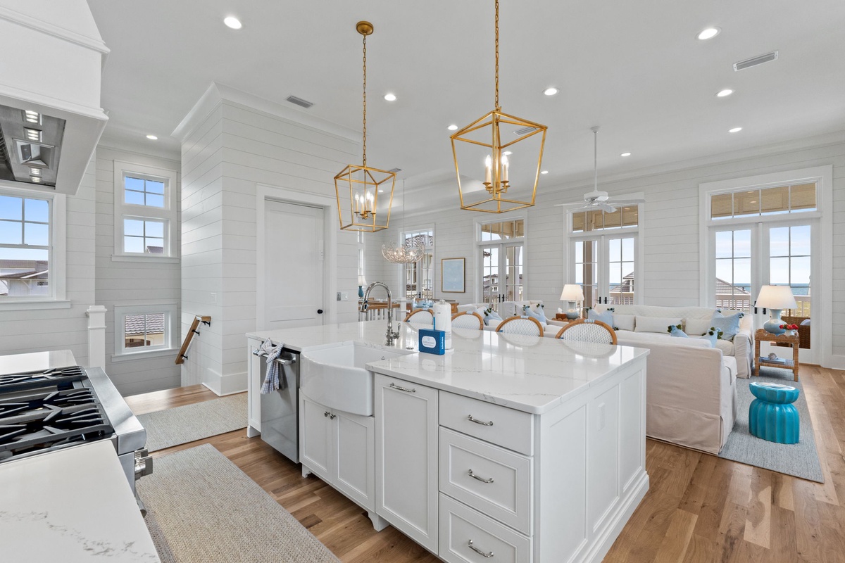 Gather around the bright kitchen island while soaking in gorgeous coastal views through walls of windows. Gold pendant lights add warmth to this open, airy space.
