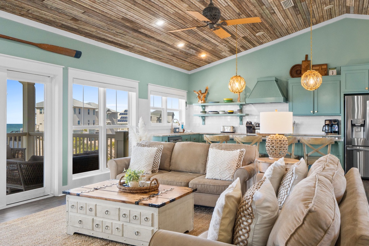 Relax in your coastal-inspired living room with soft seating, wood ceiling, and kitchen views perfect for vacation moments.