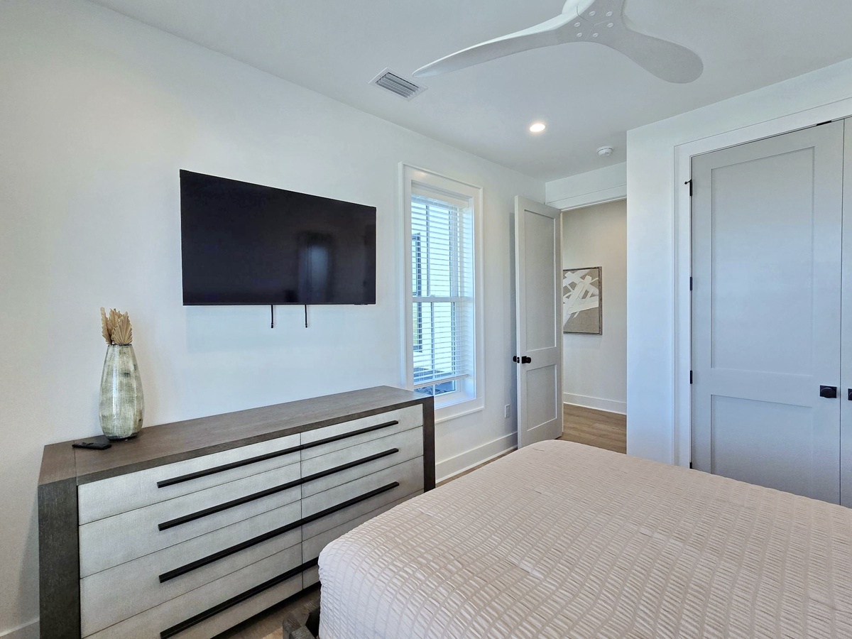 Unwind in your peaceful bedroom with modern amenities, ceiling fan, and wall-mounted TV for your entertainment.