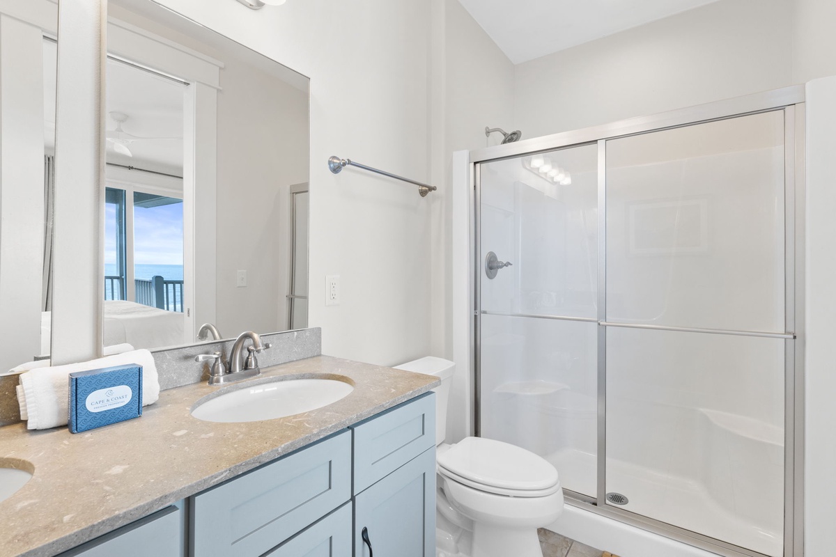 Your spacious bathroom features modern fixtures, a luxurious shower, and stunning ocean views through the mirror's reflection.