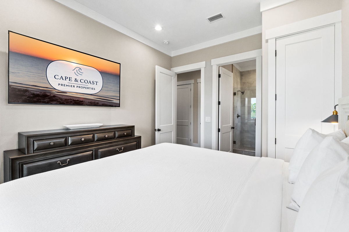 Slip into crisp white linens and unwind in your elegant bedroom, complete with rich furnishings and serene coastal artwork above.