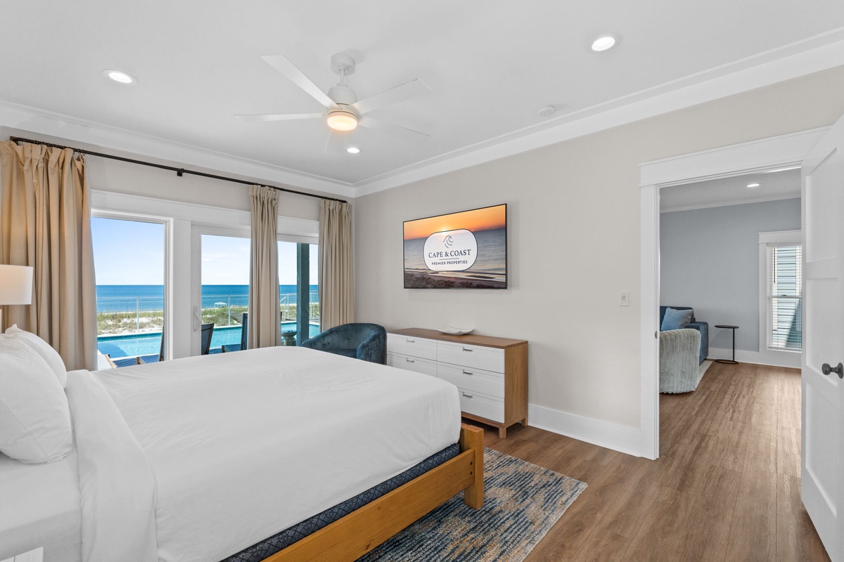 Wake up to breathtaking ocean views from your spacious bedroom, featuring a plush bed, ceiling fan, and private access to a cozy sitting area for ultimate relaxation.