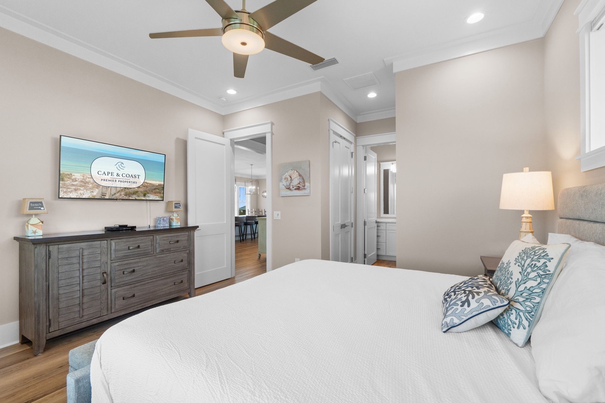 Drift off in this serene bedroom with crisp linens, coastal accents, and a ceiling fan to keep you cool. Your restful retreat awaits.