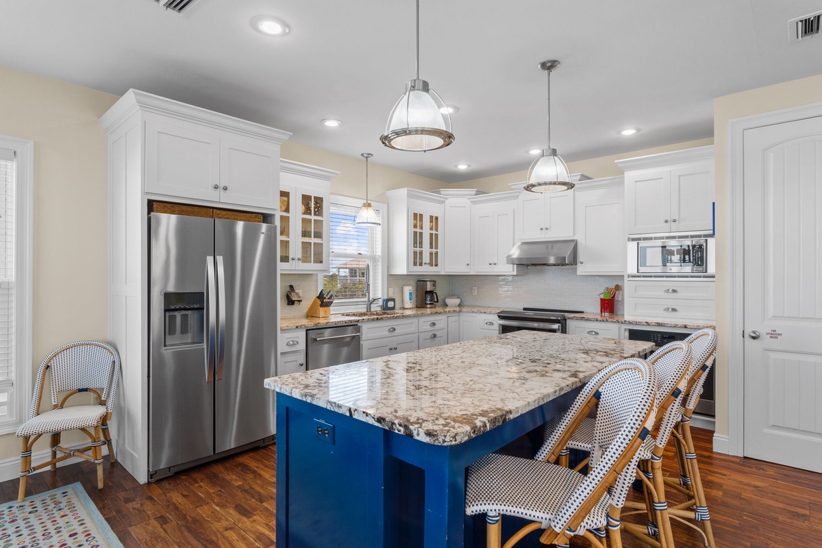 Your gourmet kitchen invites you to gather around a spacious granite island with stylish seating, where gleaming stainless appliances and custom white cabinetry make meal prep feel effortless and inspiring.