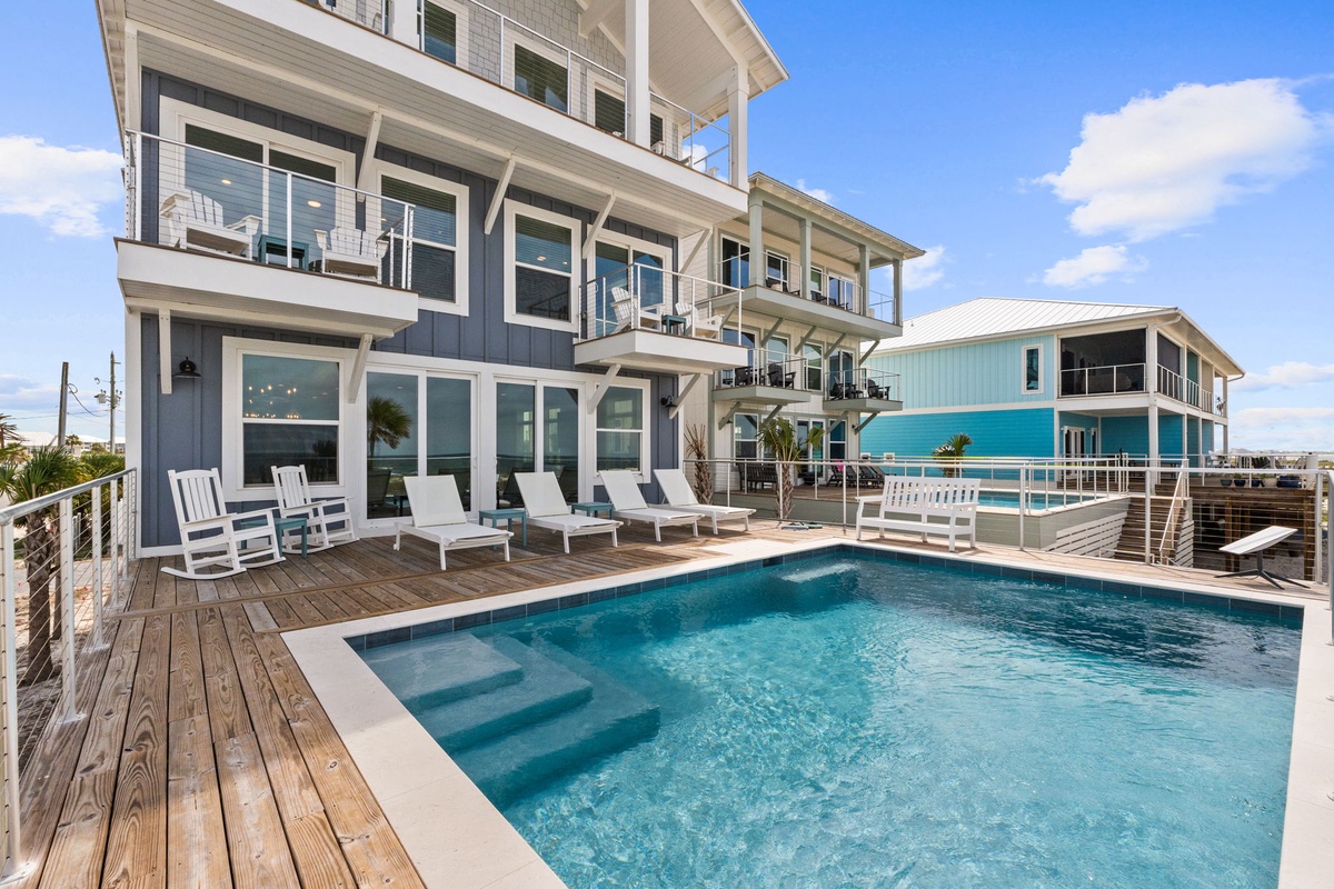 This coastal vacation home complex features multiple levels with wraparound balconies, a private swimming pool with swim-up seating, and spacious sun decks overlooking the surrounding area.