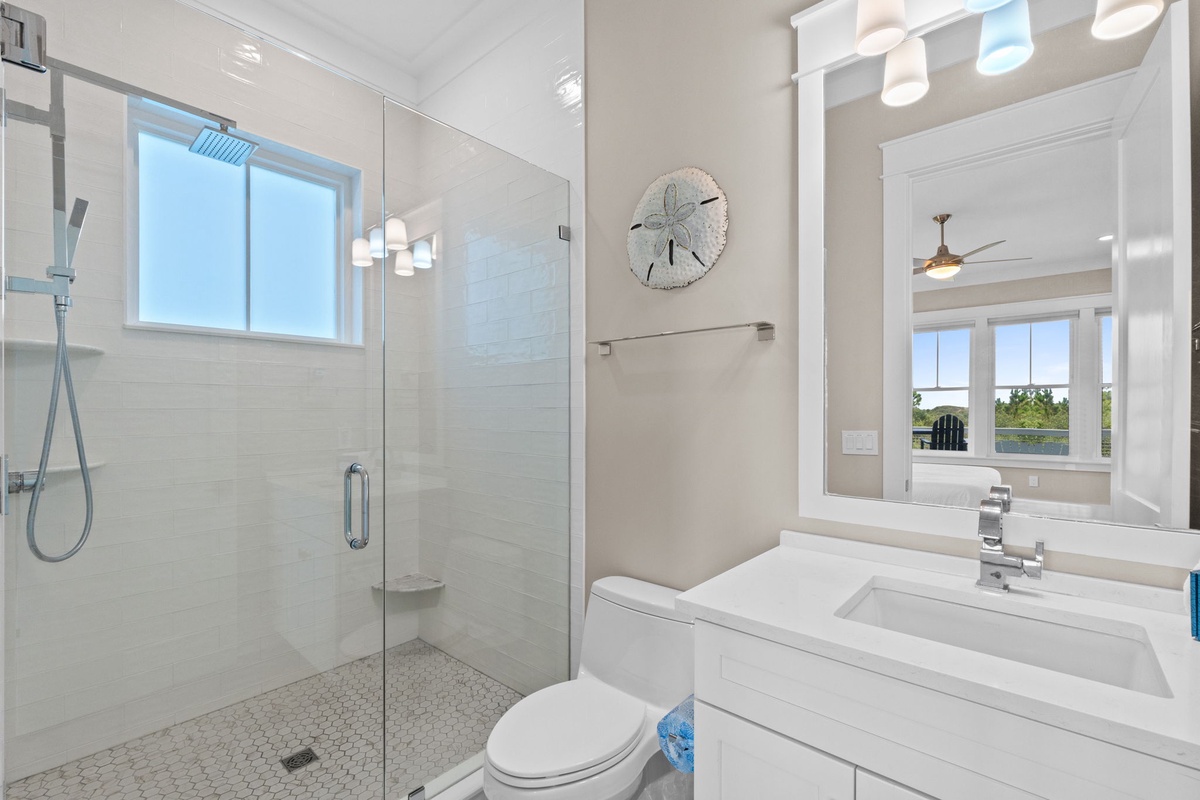 Your private bathroom features a modern glass-enclosed shower, sleek white tile, and a bright, airy design that feels both fresh and relaxing after a day of adventure.