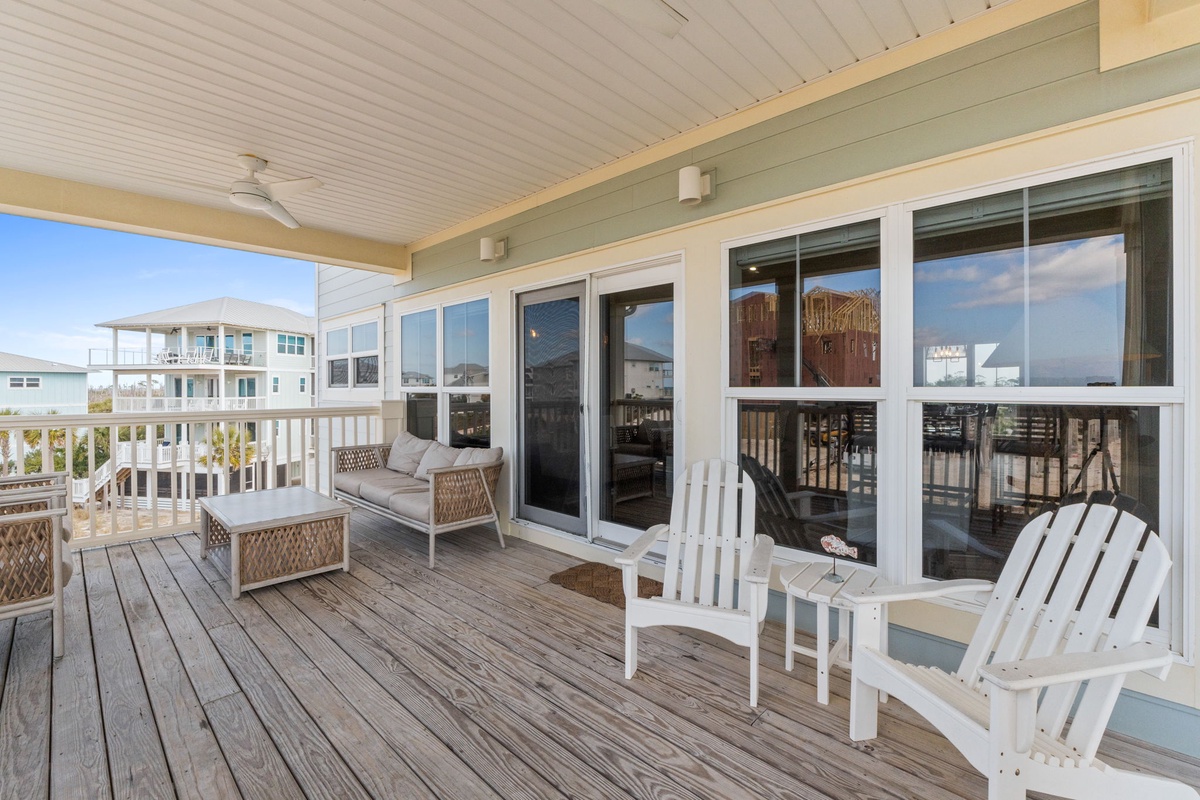 Your private deck beckons with Adirondack chairs and cozy seating, perfect for morning coffee while watching the coastal neighborhood come alive.