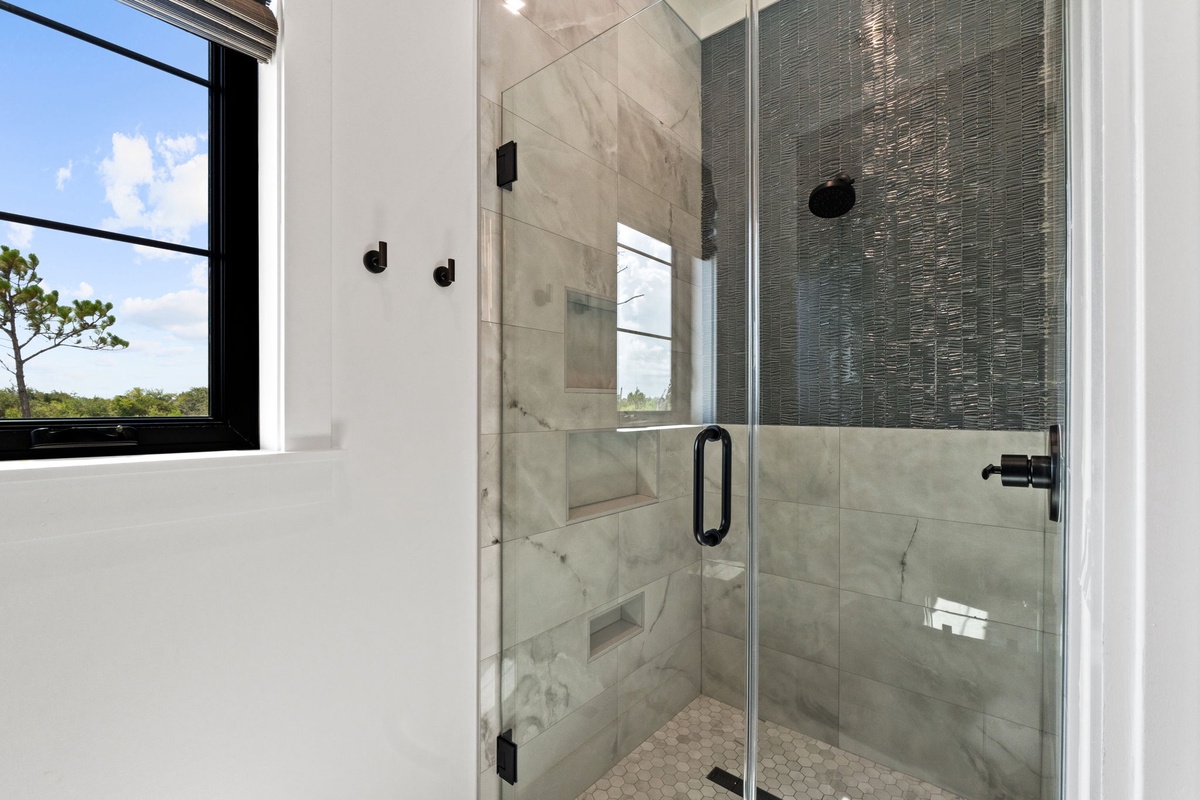 Step into your private spa-like shower featuring sleek marble tiles, modern black fixtures, and a built-in bench—perfect for unwinding after a day of adventure.