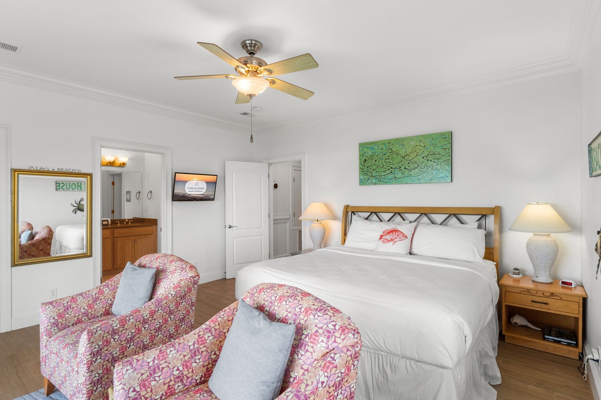 Unwind in your bright bedroom with a plush king bed, cozy seating, ceiling fan, and coastal touches that make you feel right at home by the water.