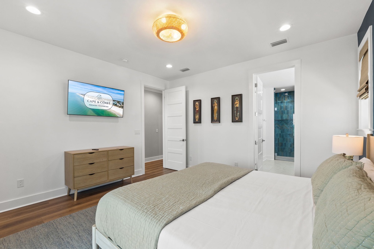 Step into your serene coastal retreat, where crisp white walls and warm wood floors create a calming sanctuary. Unwind in plush bedding while enjoying your favorite shows on the wall-mounted TV, with an elegant en-suite just steps away.