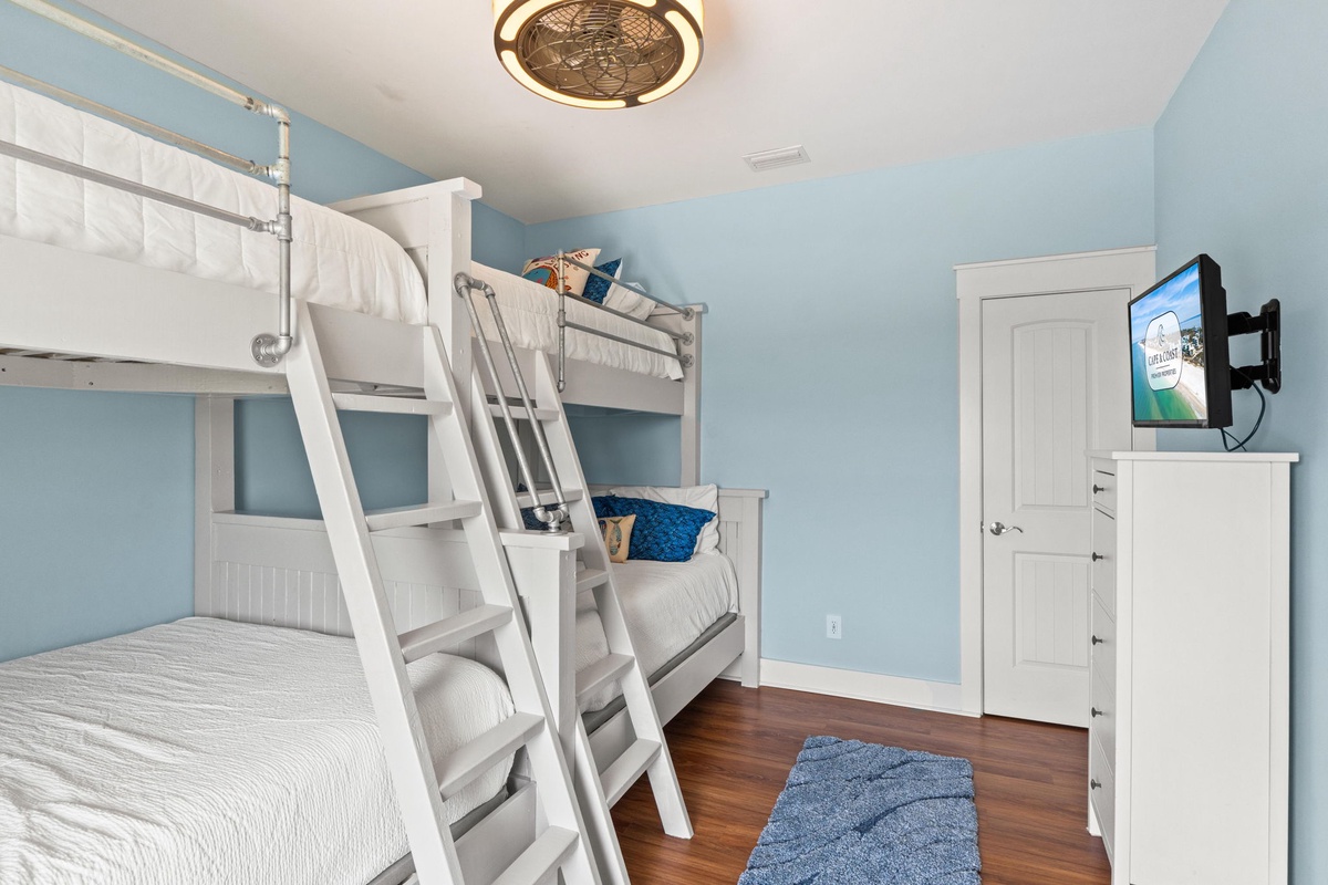 Settle into your coastal-themed bedroom with crisp white bunk beds and bright blue accents. Unwind with your favorite shows on the wall-mounted TV or cozy up in soft linens after a long day exploring.
