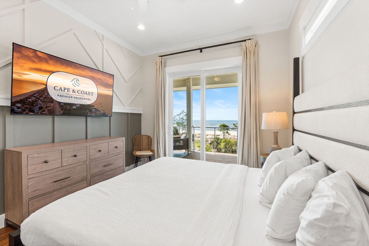 Wake up to stunning ocean views from your private balcony in this serene bedroom with plush linens and modern amenities.