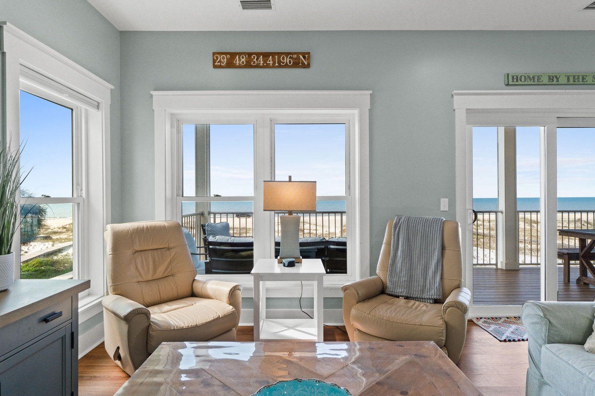 Sink into plush leather recliners and gaze through floor-to-ceiling windows at breathtaking ocean views. The soothing coastal palette and warm hardwood floors create your perfect beachside sanctuary.