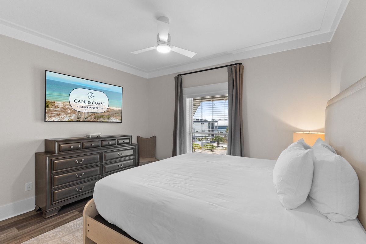 Sink into crisp linens in your restful bedroom, cooled by a ceiling fan and warmed by coastal light from your window overlooking nearby buildings.