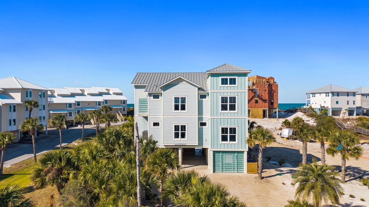 Beachfront property with stunning coastal architecture surrounded by swaying palm trees and neighboring vacation homes.