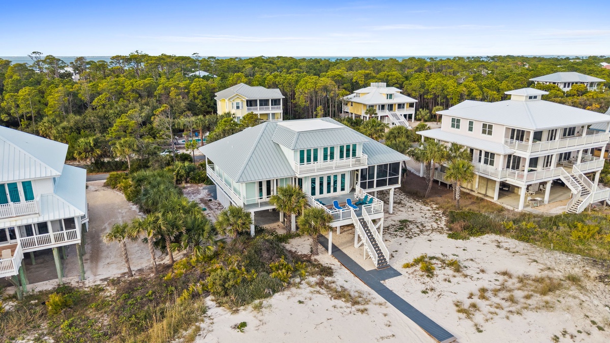 Elevated coastal homes nestled among lush vegetation and pristine sandy surroundings in a peaceful beachside community.