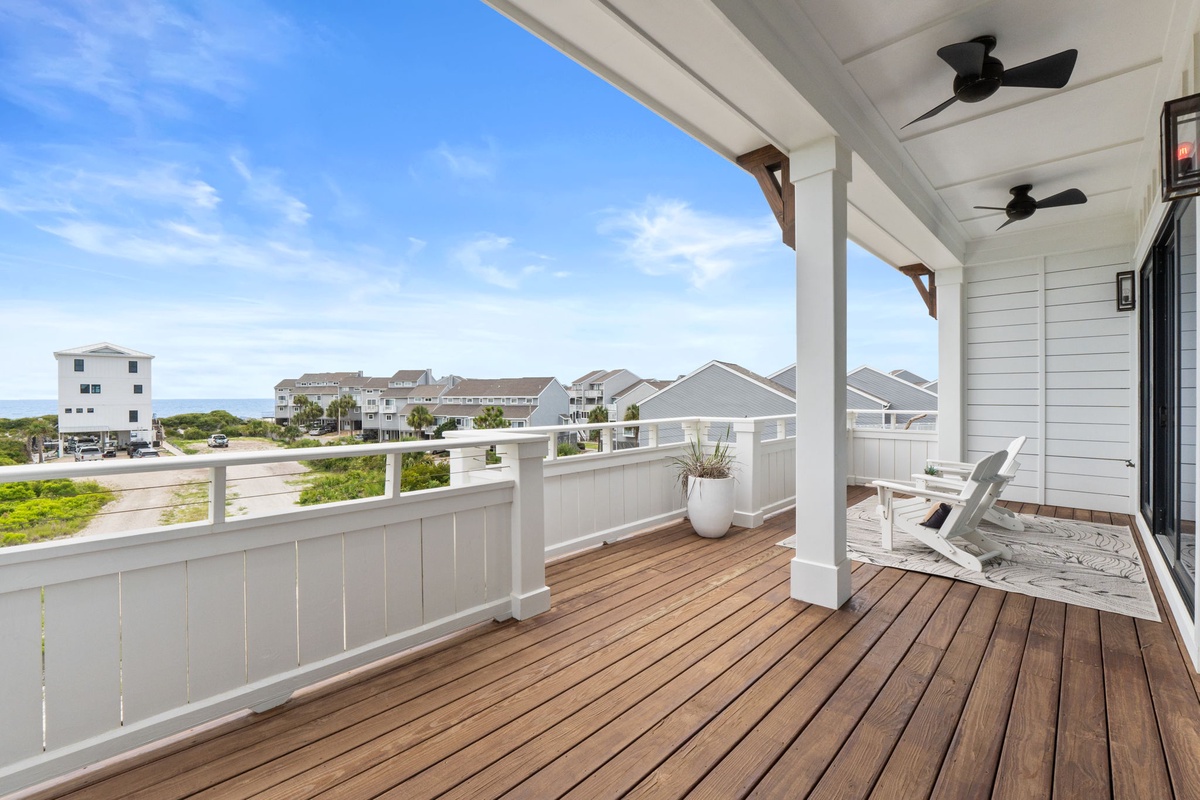 This coastal vacation rental offers a large covered balcony overlooking nearby beachfront properties and the ocean beyond, providing an ideal spot for morning coffee or evening relaxation.