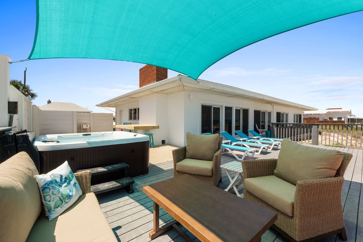 Your private beachfront deck features a hot tub, lounge chairs, and comfortable seating under a turquoise shade sail—perfect for sunset evenings or morning coffee by the ocean.