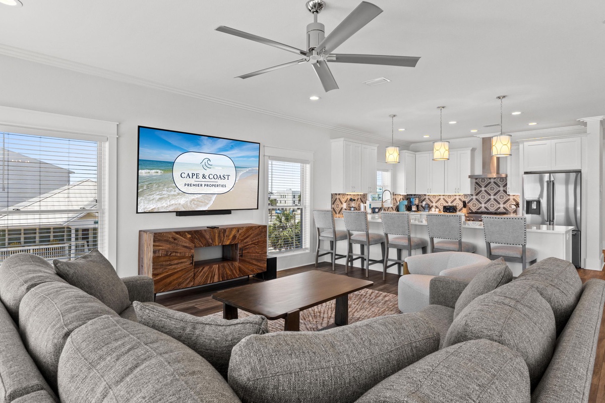Sink into plush seating in this open-concept living space, where your morning coffee meets ocean breezes and conversation flows as easily as the natural light through the windows.