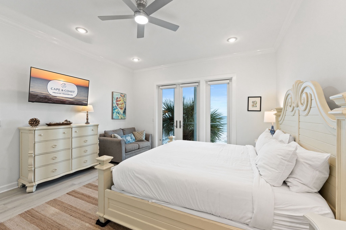 Drift off in your coastal-inspired bedroom with crisp white linens, ceiling fan, and French doors opening to tropical views.