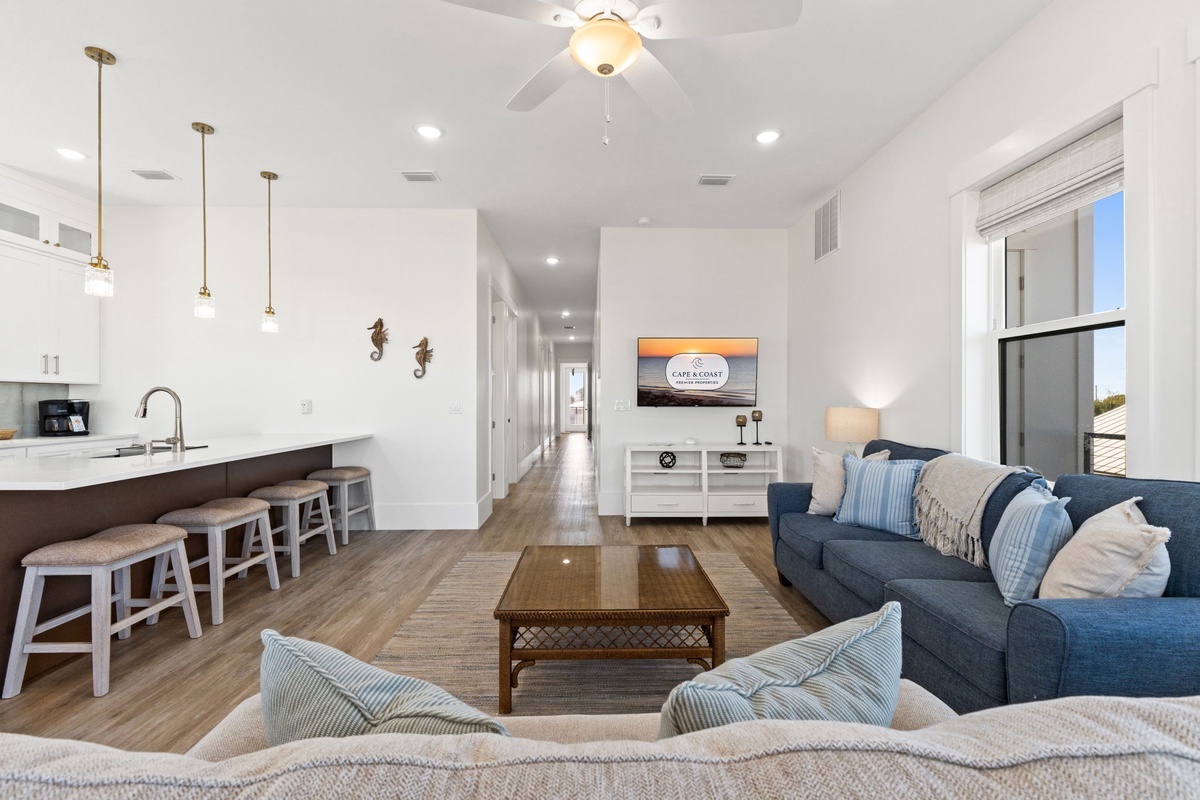 Unwind in your bright, coastal-themed living space with plush seating and open kitchen—perfect for relaxing after beach days.