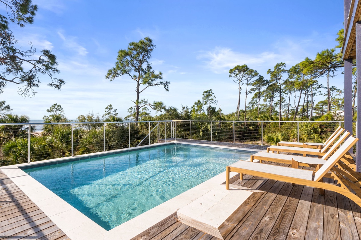 Dive into crystal-clear waters while soaking up ocean views from your private pool deck, surrounded by coastal pines.