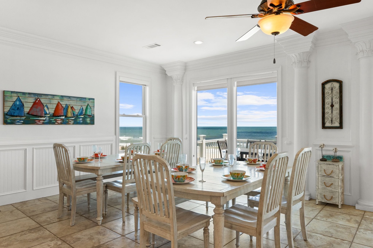 Imagine dining with a stunning sea view through expansive windows. The bright, coastal-themed space features elegant ceiling details and comfortable seating for your group.