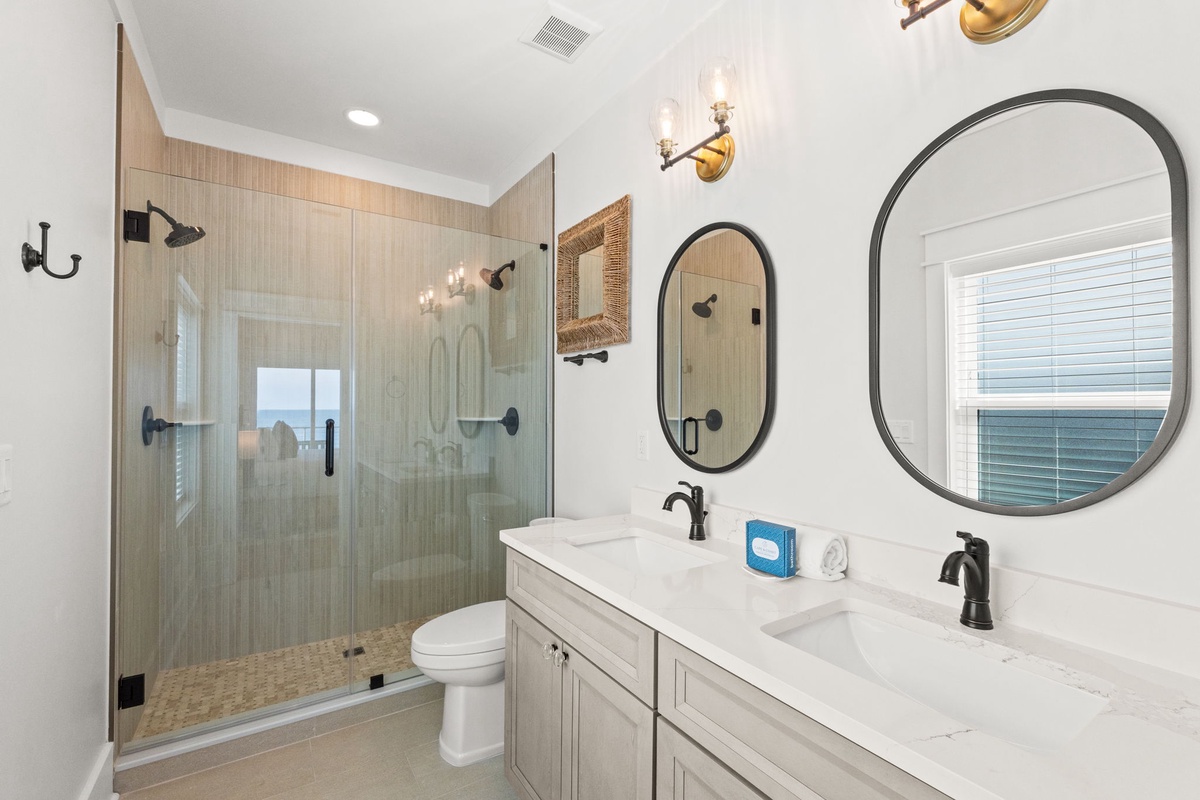 Refresh in your stylish bathroom featuring a spacious walk-in shower, dual vanities with elegant mirrors, and coastal-inspired design that makes your mornings feel like a getaway.