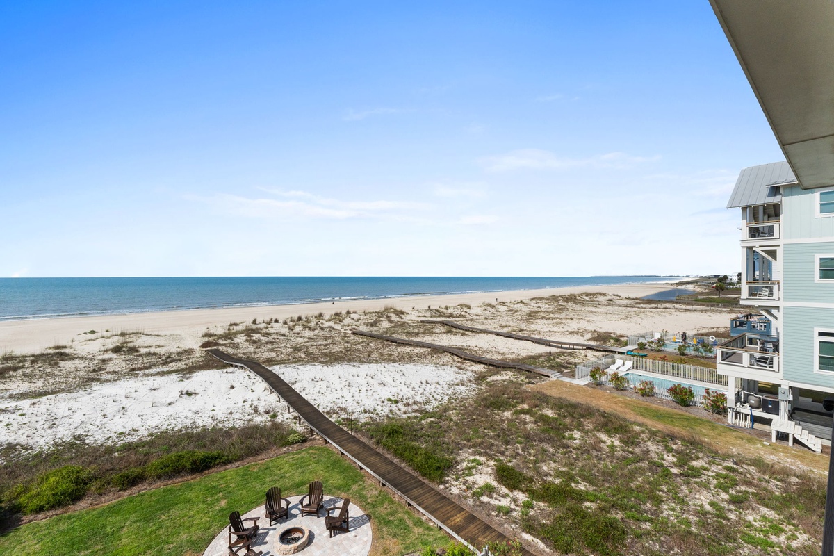Elevated coastal property positioned between sandy dunes and the Gulf shoreline, with beachfront homes nearby and boardwalk access to the water.