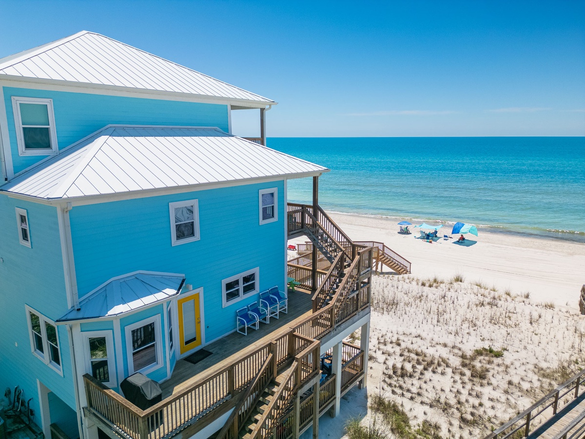 A vibrant beachfront property with direct access to soft white sands and turquoise waters stretching to the horizon.