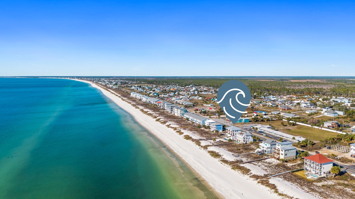 Stunning aerial perspective of pristine white sand beach stretching along turquoise waters, showcasing the beautiful coastal community surrounding the property.