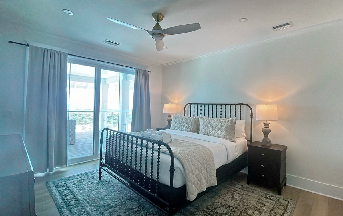Drift off in this serene bedroom with a plush bed and gentle ceiling fan to keep you cool, all while views of the coast beckon through your balcony doors.