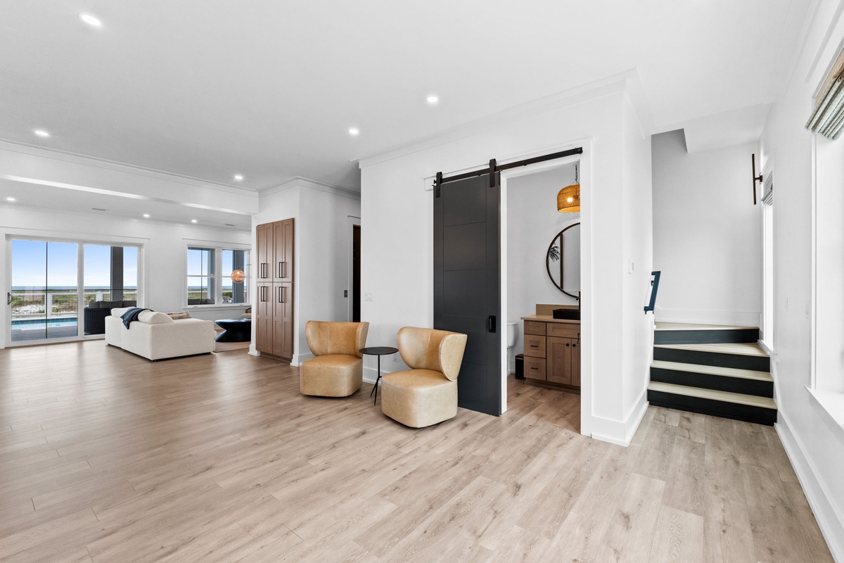 Your spacious open-plan living area features stylish modern design, warm wood floors, and a striking barn door that adds a cozy farmhouse touch to your coastal retreat.