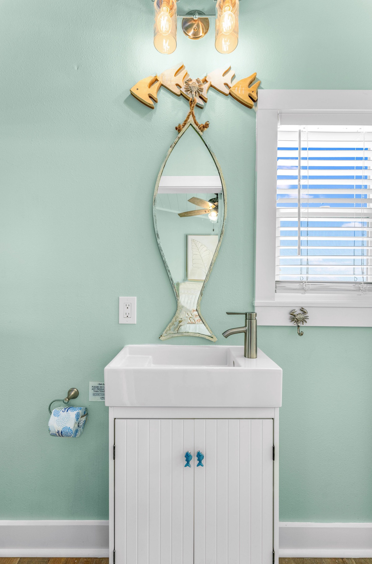 Freshen up in your charming coastal bathroom with its soothing mint walls, playful fish mirror, and beachy maritime touches throughout.