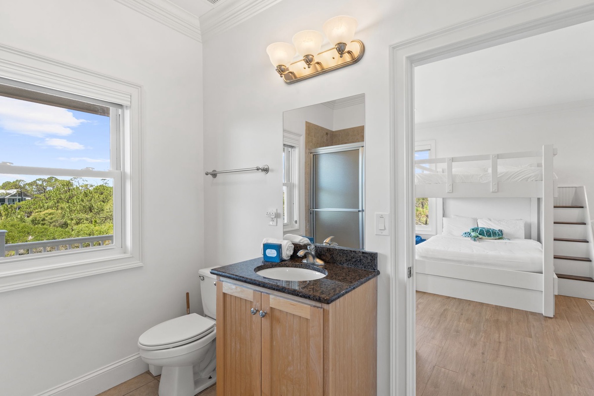 Your private bathroom features a granite vanity, bright lighting, and a convenient shower—a peaceful spot to refresh with garden views through the window.
