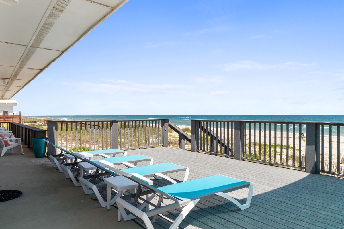 Expansive beachfront terrace overlooking turquoise waters, featuring comfortable sun loungers for soaking up coastal breezes and uninterrupted ocean views.
