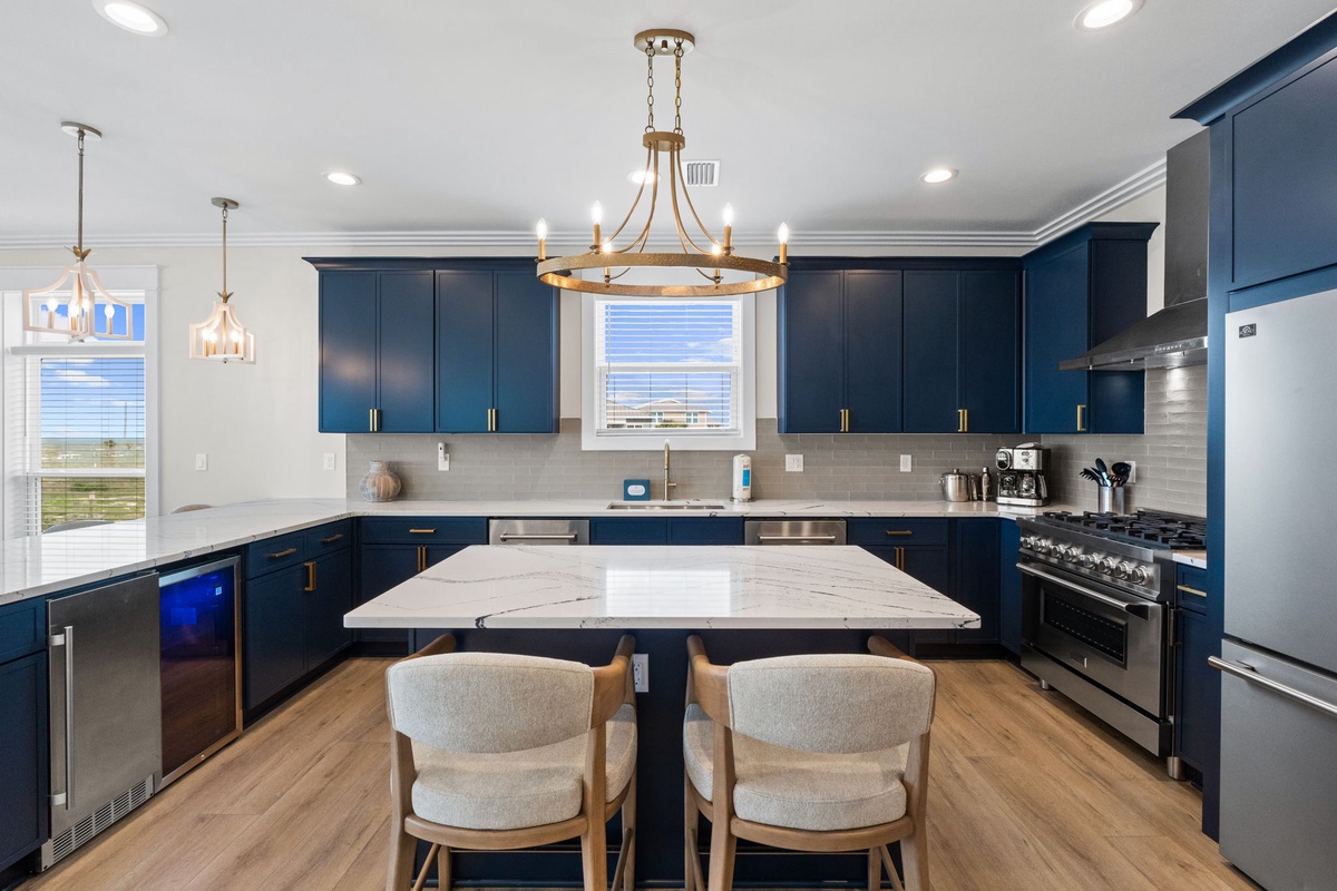 This spacious kitchen welcomes you with rich navy cabinetry, gleaming marble-topped island, and abundant natural light. Prepare meals on professional-grade appliances while enjoying beautiful views through the windows.