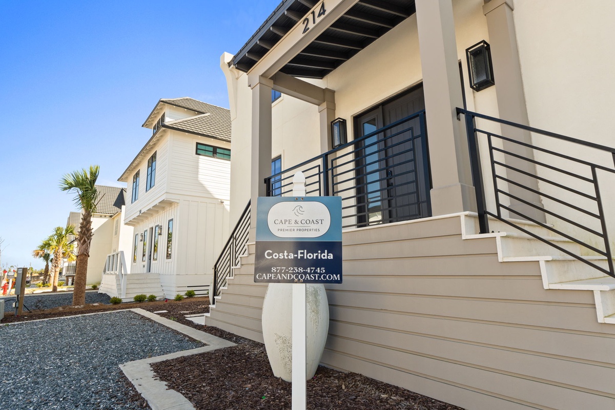 Modern coastal rental properties with contemporary architecture and professional property management signage in a well-developed beachside community.