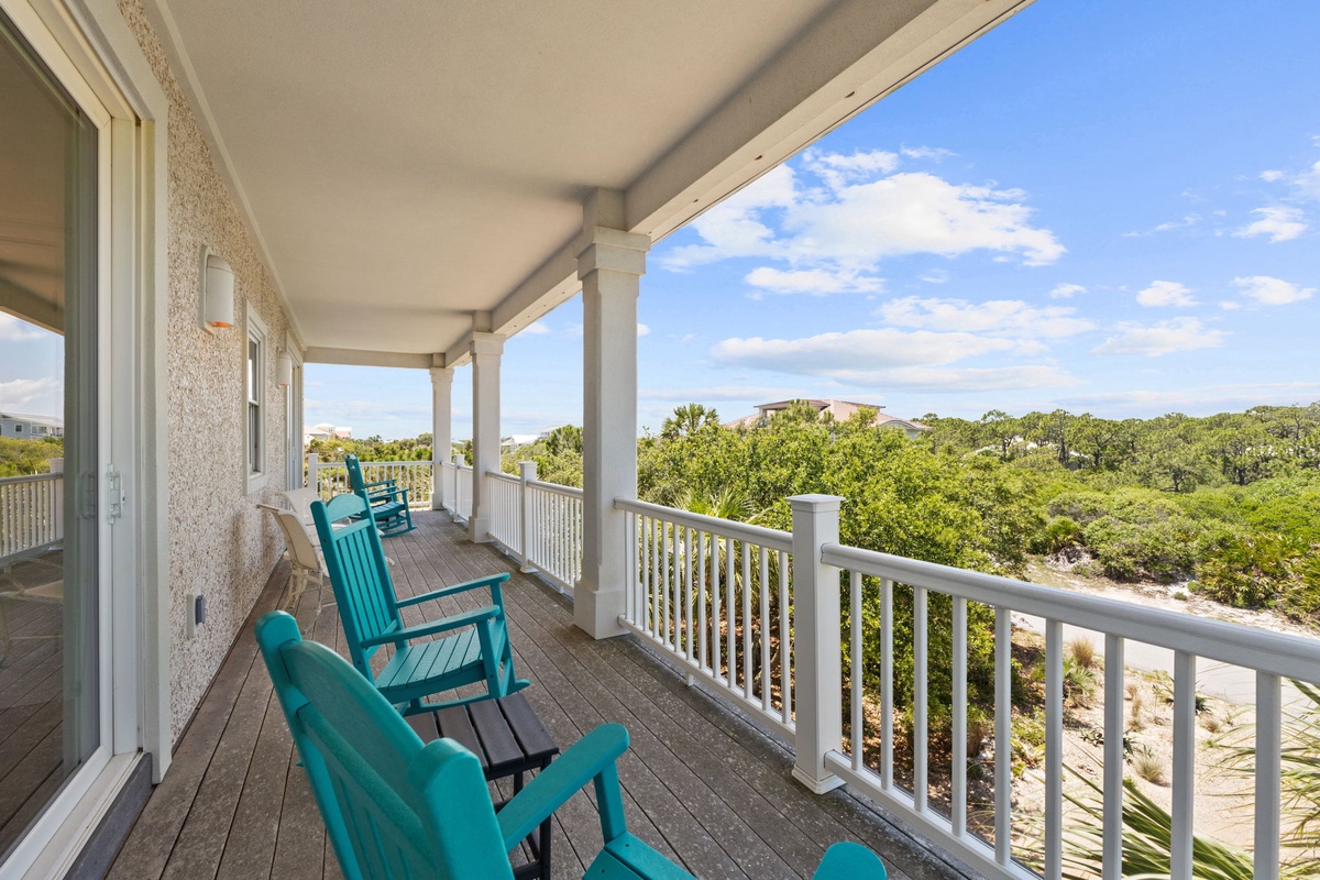 Step out onto your private balcony where turquoise rocking chairs invite you to unwind and soak in sweeping views of lush greenery and coastal sky.