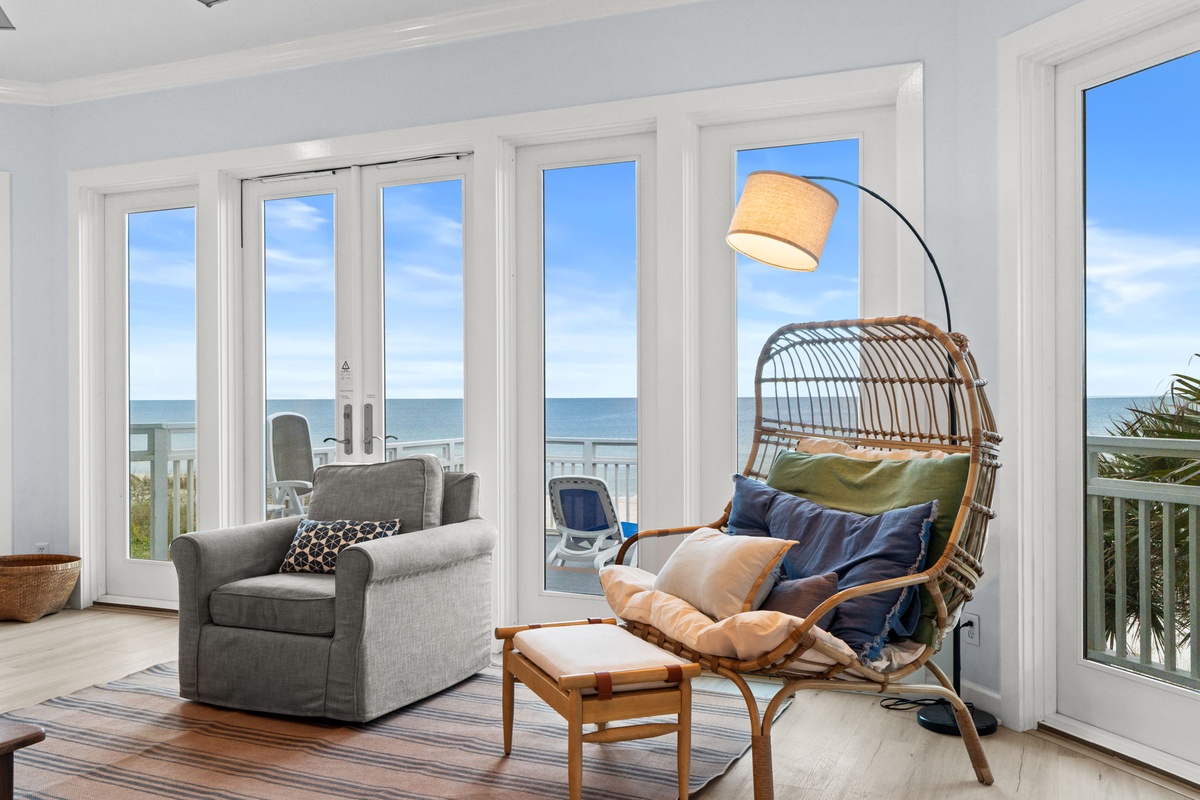 Sink into your wicker hanging chair with ocean breeze flowing through floor-to-ceiling windows, creating your perfect seaside sanctuary.