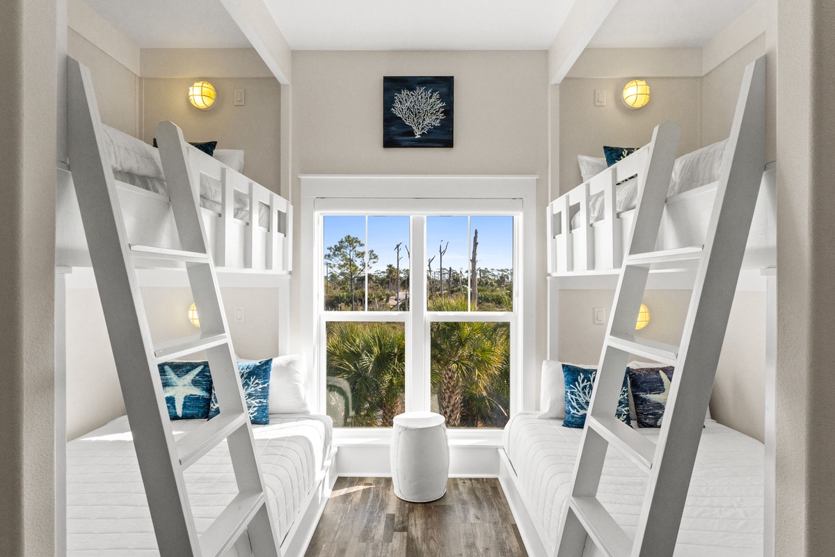 Rest comfortably in this bright, nautical-themed bunk room featuring built-in beds and coastal views through the large window.