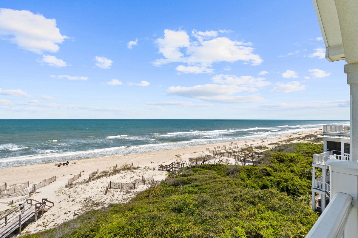 Beachfront property offering scenic ocean and sandy shoreline views from balcony areas. Natural coastal landscape with dune vegetation and boardwalk access to the beach.