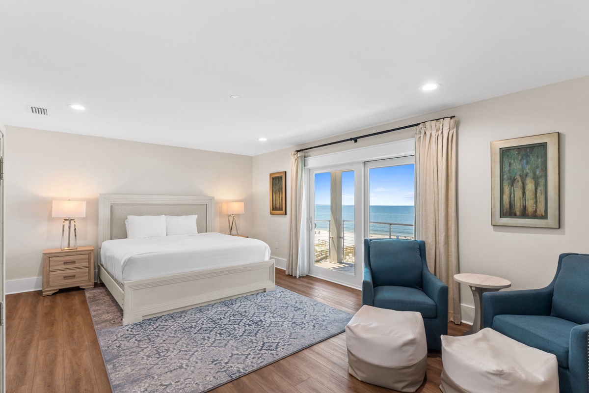 Wake up to stunning ocean views from your private balcony. This serene bedroom features a plush king bed, cozy seating area, and elegant coastal decor—your perfect seaside retreat awaits.