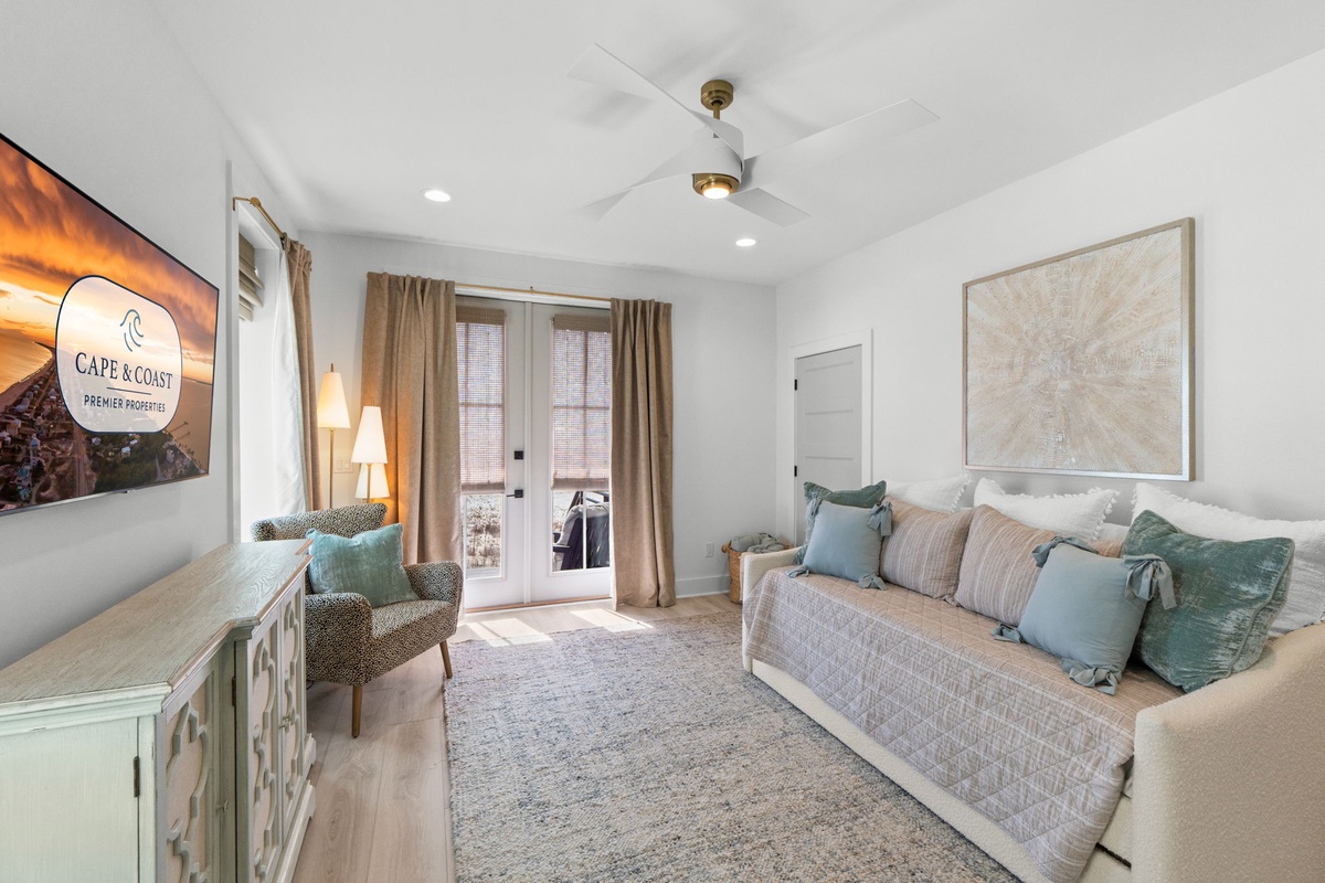 Sink into plush seating with ocean-hued pillows while natural light streams through French doors to your private balcony in this serene coastal retreat.